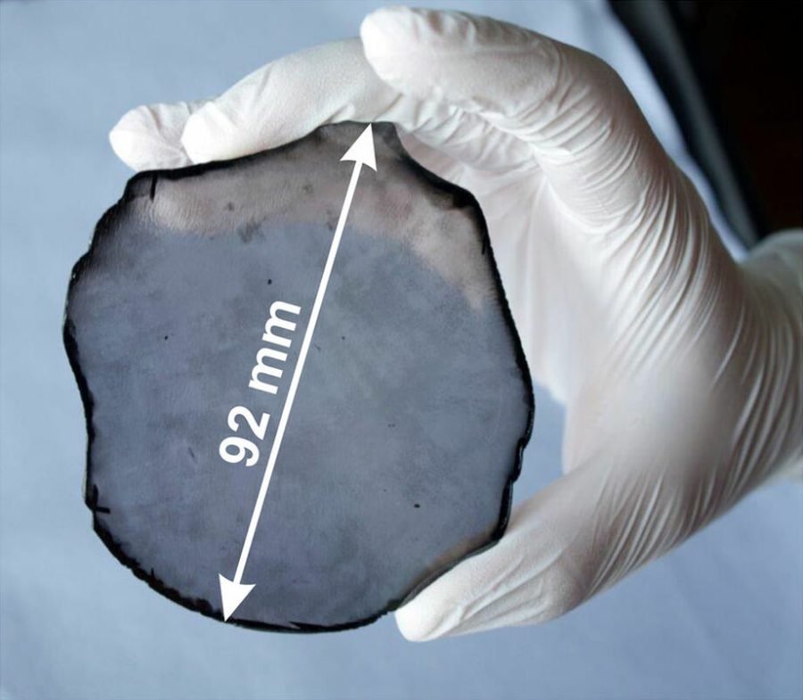 A gloved hand holding a thin, dark, roughly circular diamond disc, with an arrow marking its 92 millimetre width.