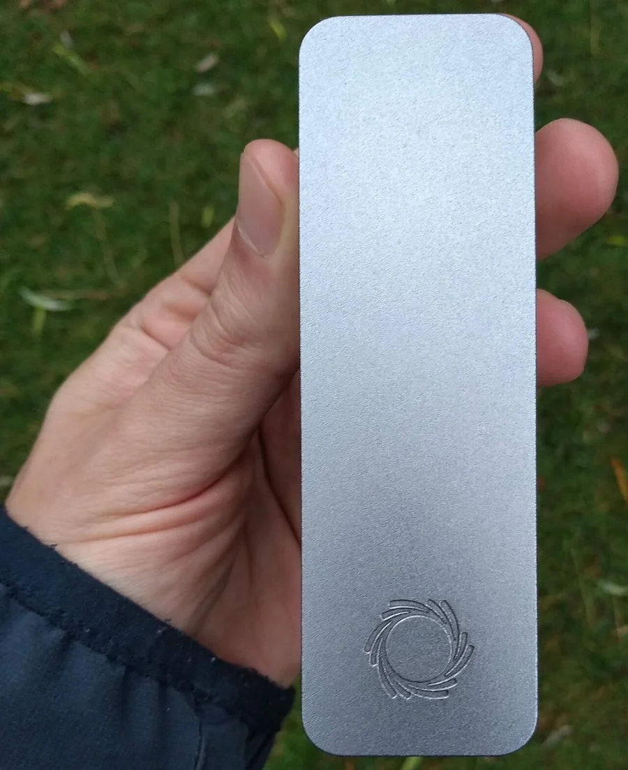 A hand holding a small grey metal sequencing device the length of a palm.