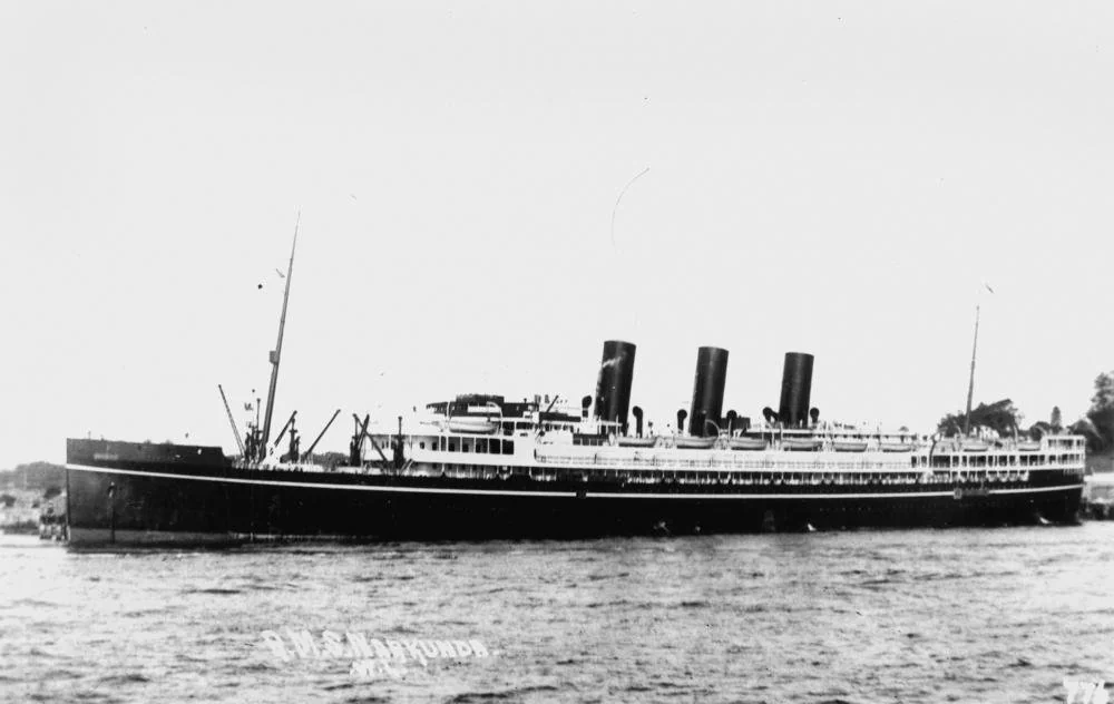 The R.M.S. Narkunda, a long black-hulled liner with three funnels, moored in calm water.