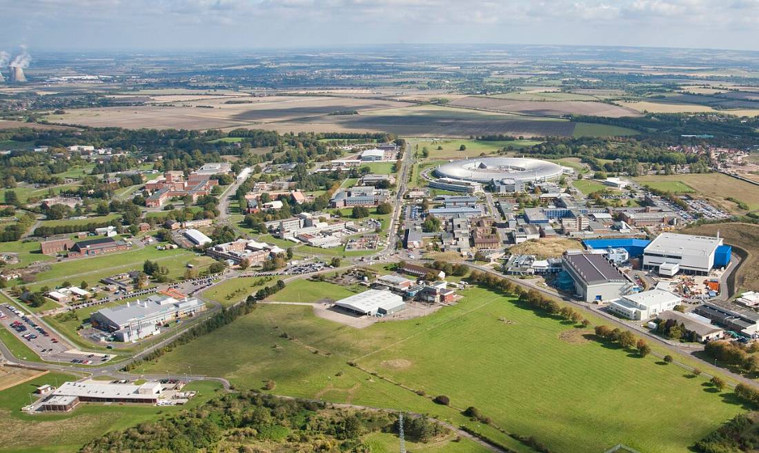 Aerial view of a science campus of low buildings set among green fields.